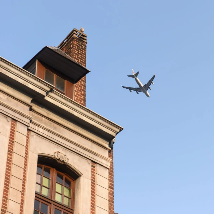 Un avion vole au-dessus d'un bâtiment dans un ciel bleu